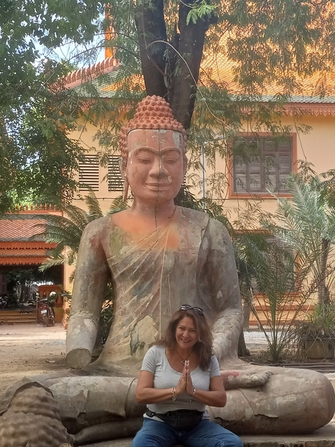 Large statue of a monk with a building in the background.