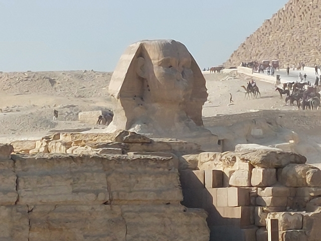       The Great Sphinx of Giza in the desert with tourists nearby.
  