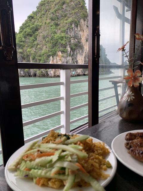 View through a boat window showing water and limestone cliffs.