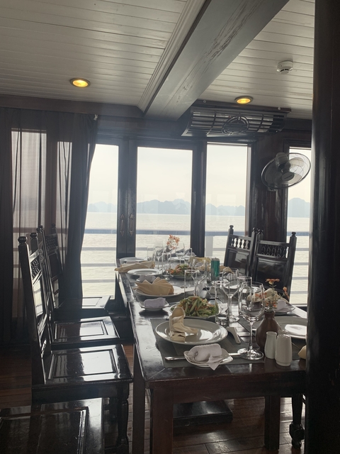 Dining table on a boat with ocean view through windows.