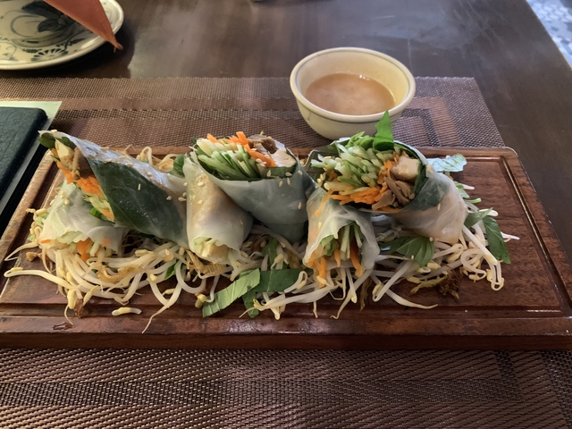 Plate of fresh spring rolls with dipping sauce on a table.