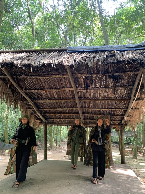 People dressed in military uniforms under a thatched roof.