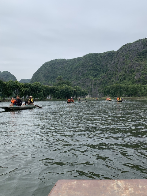 Small boats on a river surrounded by lush green mountains.