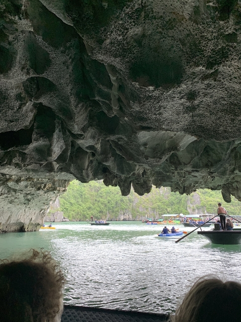 View from inside a cave opening to water and boats outside.