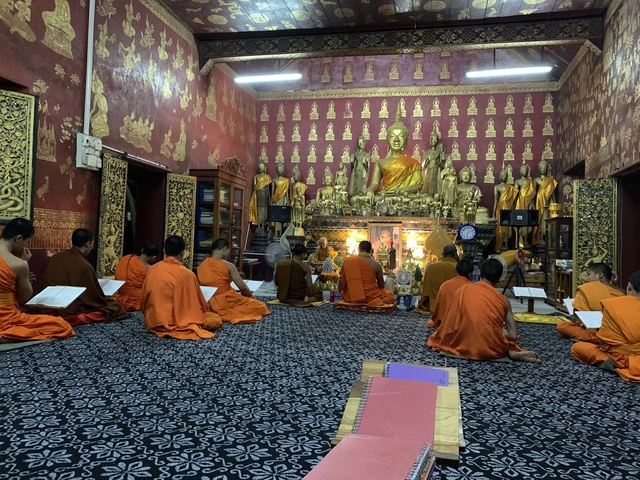 Monks in an ornately decorated temple interior.