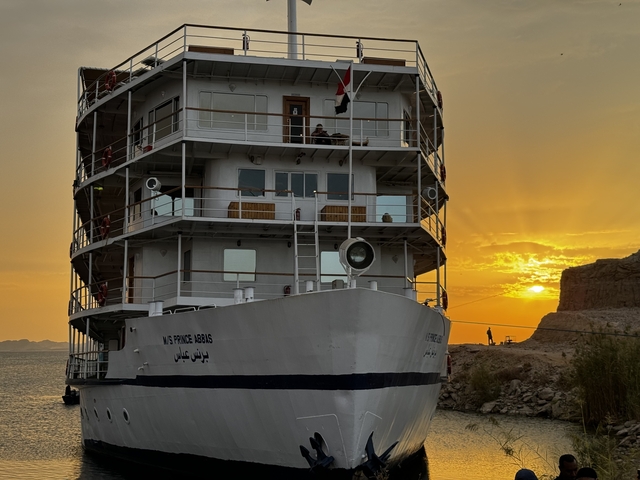 A large cruise ship at sunset on a river.