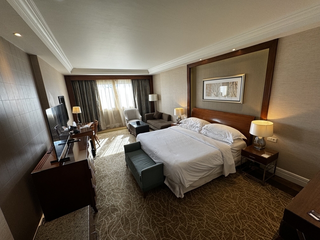       A hotel room interior with a bed, sofas, and television.
  