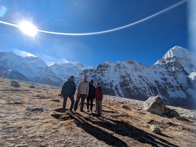       Group posing on a snowy mountain with a clear sky.
  