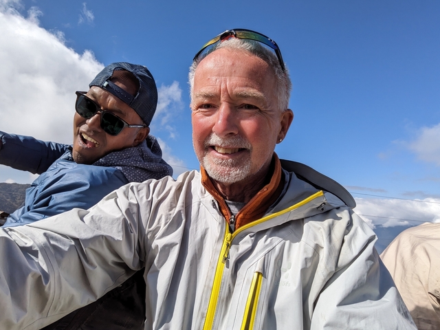       Two smiling people posing with a mountain backdrop.
  