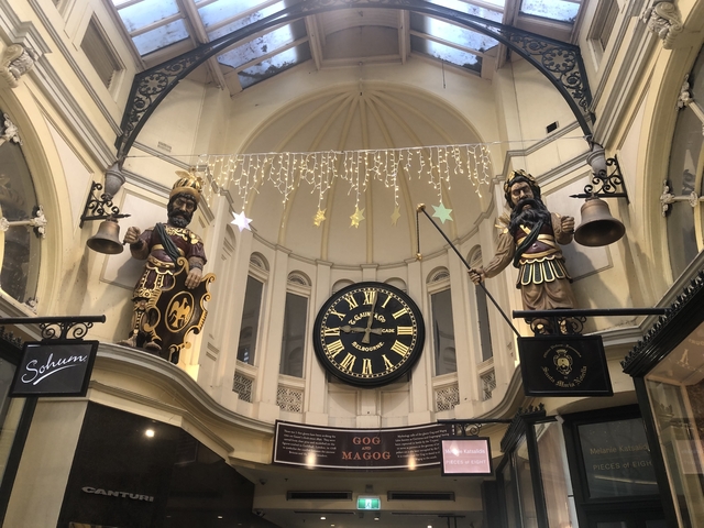       Interior of a building with a large clock and decorative sculptures.
  