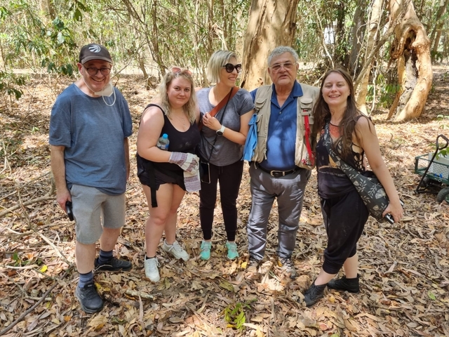       Group of people standing in a forested area.
  