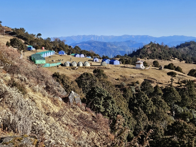 Tent campsite in a mountainous region under a blue sky.