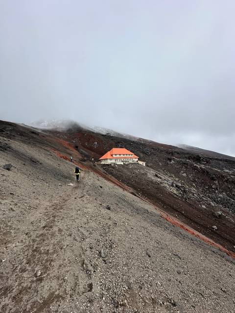 Building on a rocky slope with cloudy background.