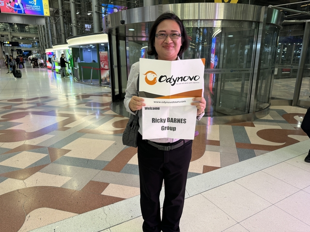       Person holding a welcome sign at an airport entrance.
  
