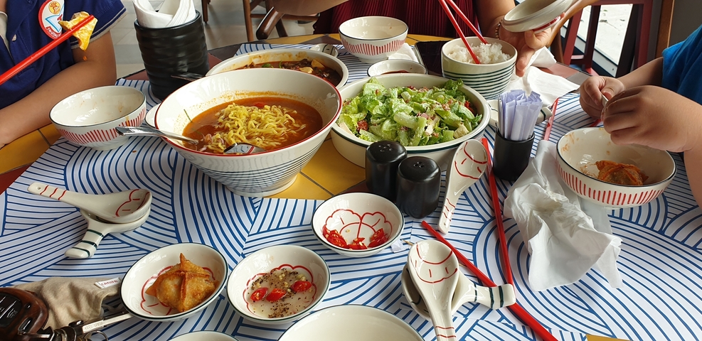      A table full of traditional Vietnamese dishes with people dining.
  