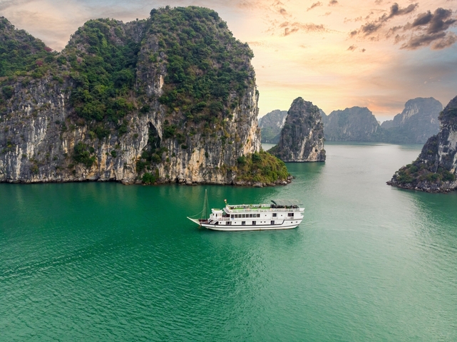       A cruise ship sailing through the stunning limestone karsts in Halong Bay.
  
