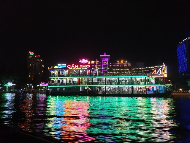 Colorful riverboat at night with vibrant reflections in the water.