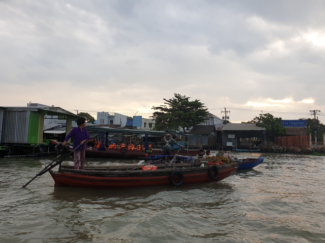 People on boats at a floating market in a river setting.