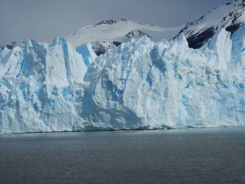 Solid ice formation part of a glacier with snowy peaks.