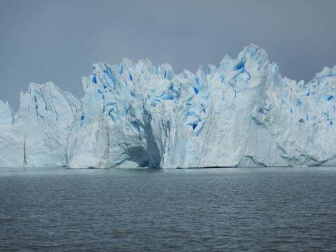 Expansive glacier with blue ice and water in the foreground.
