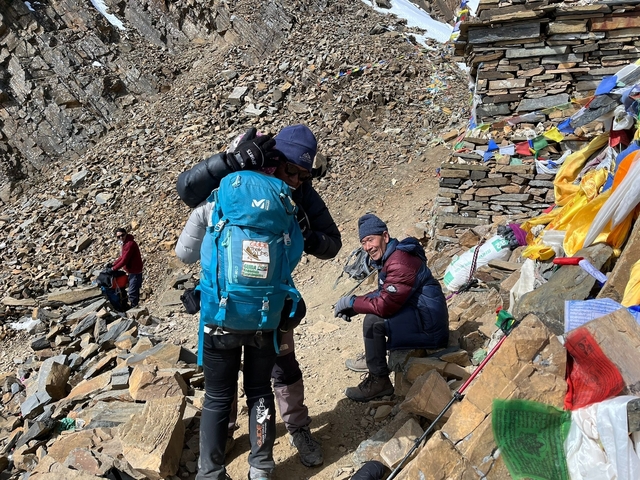      Hikers with backpacks taking a break on a rocky trail.
  