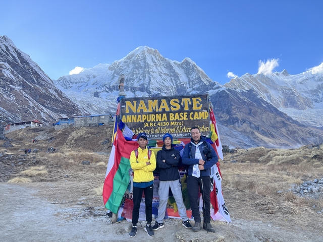       Group posing at Annapurna Base Camp with the Himalayas in the background.
  