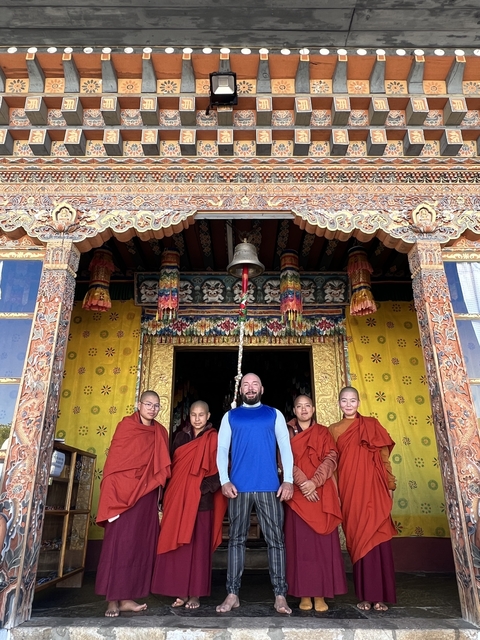       Group photo with monks in front of an ornately decorated building.
  