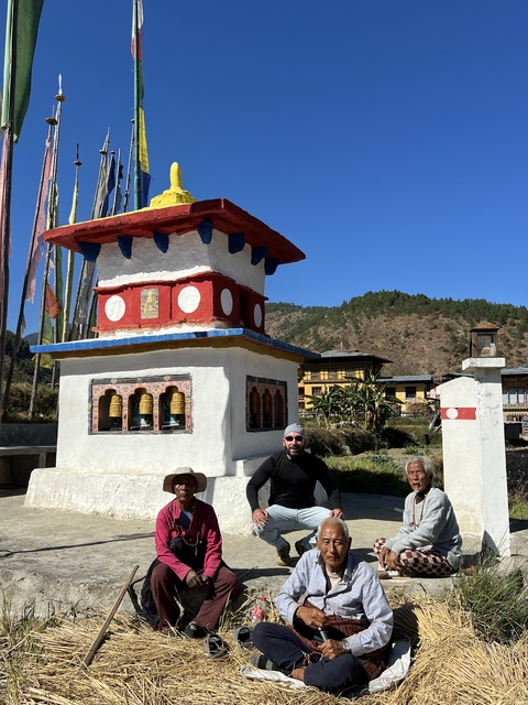       Man posing near a small Bhutanese structure.
  
