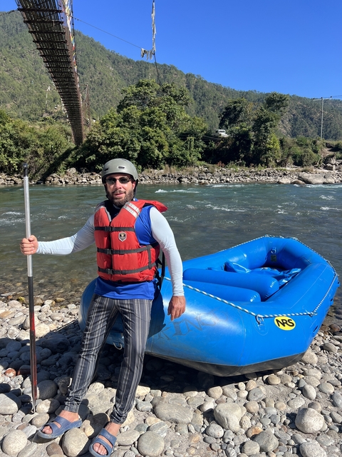       Man prepared for rafting with a river in the background.
  