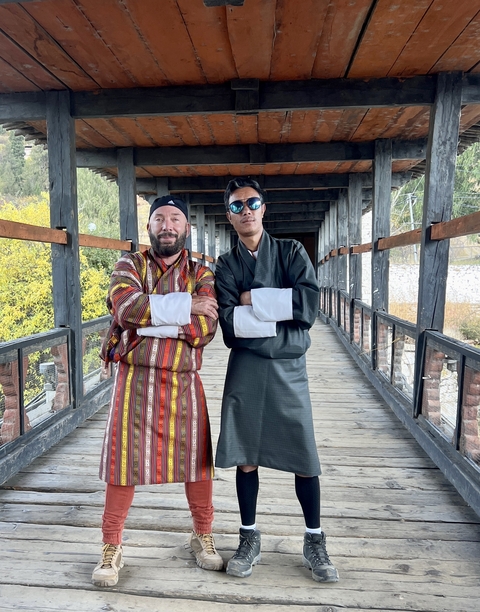       Two men in traditional Bhutanese attire on a bridge.
  