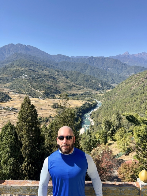       Man standing with a view of the valley and river below.
  
