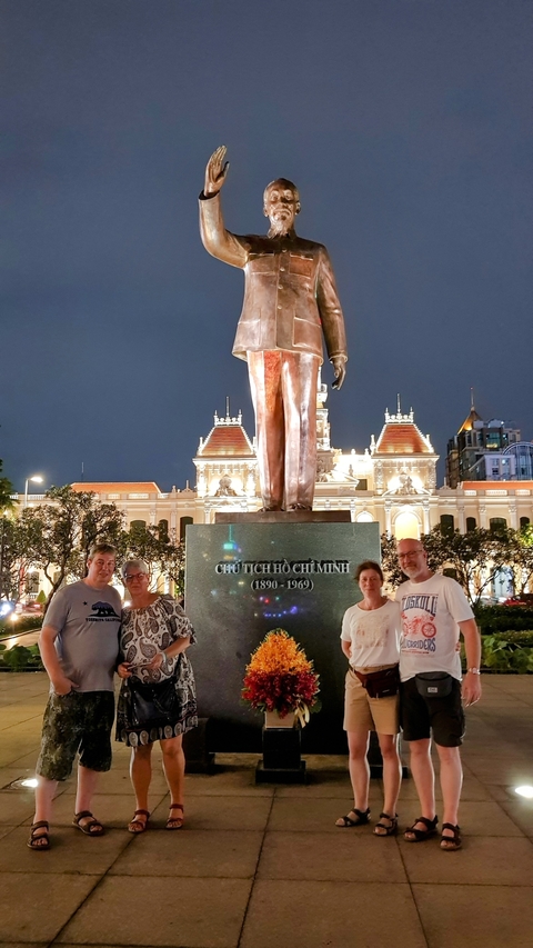 People posing in front of a statue of Ho Chi Minh at night