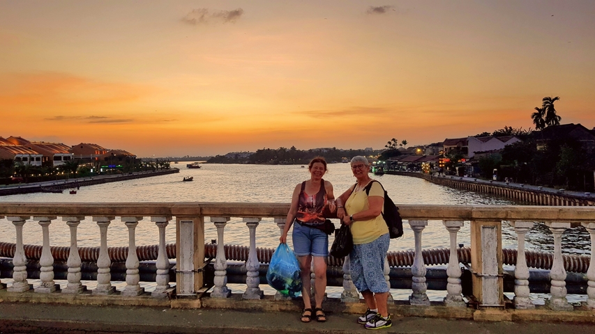 Two people posing on a bridge at sunset