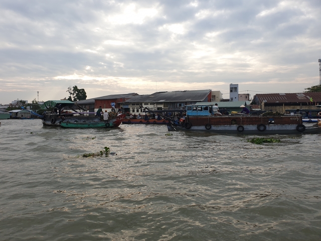 Boats on a river with cloudy skies.