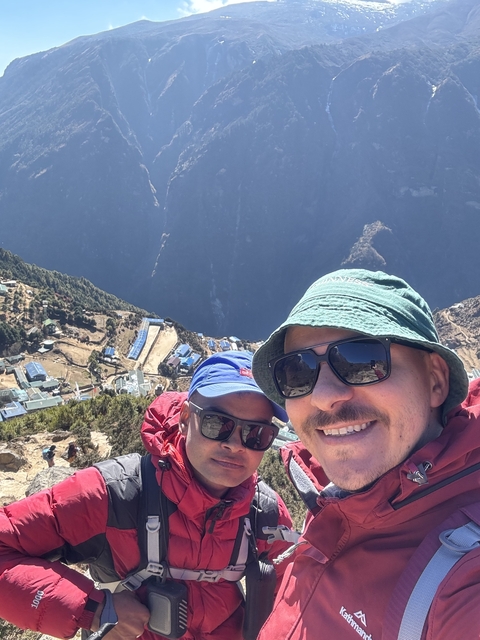       Two men taking a selfie with a mountainous background.
  