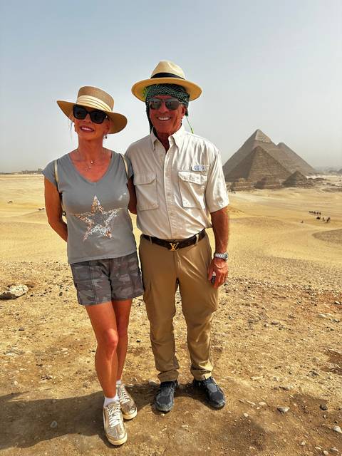 Two people posing with pyramids in the background.