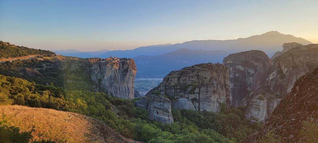       Cliff formations with a small building and valley view.
  