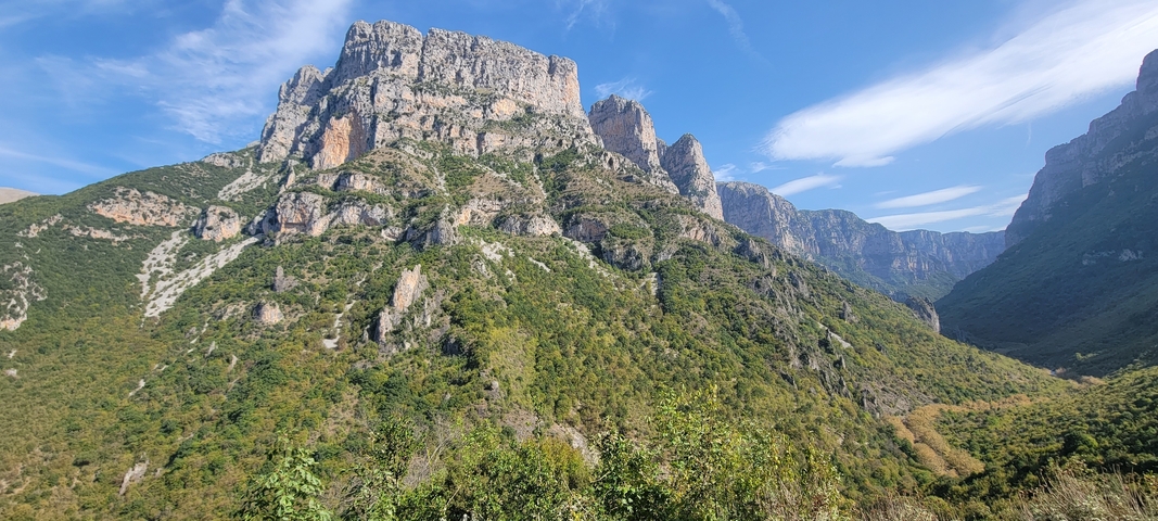       Mountain landscape with rocky cliffs and green valleys.
  