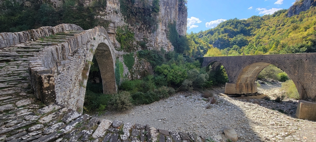       Old stone bridges crossing a riverbed.
  