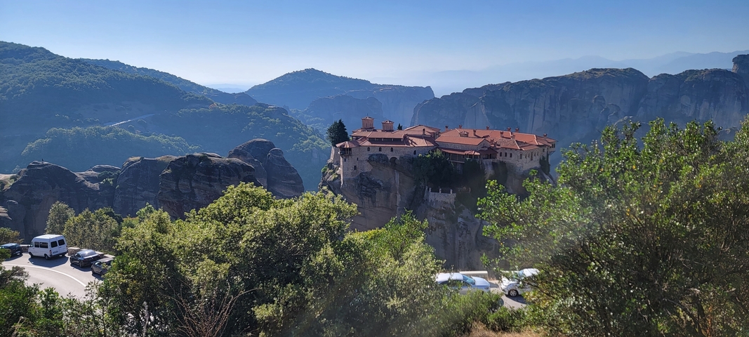       Monastery perched on a rocky outcrop with a mountainous background.
  