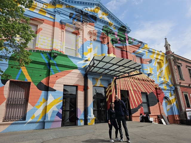 Colorful building with a painted facade and two people posing.