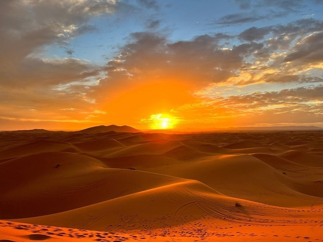       Sunset over sand dunes with a dramatic sky.
  