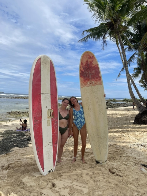 Two people holding surfboards on a beach.