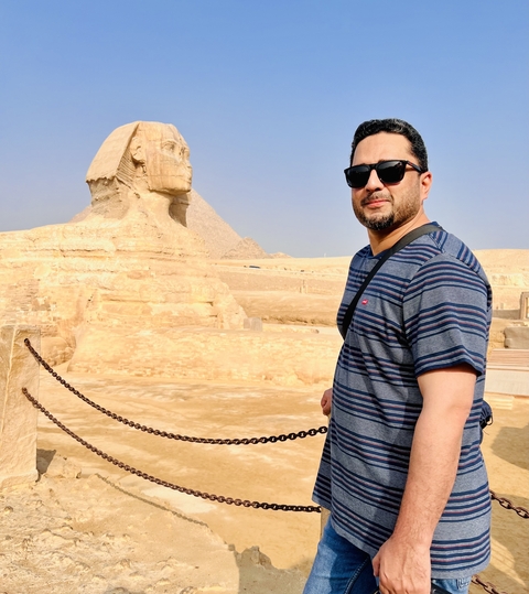       Person posing in front of the Sphinx and pyramid.
  