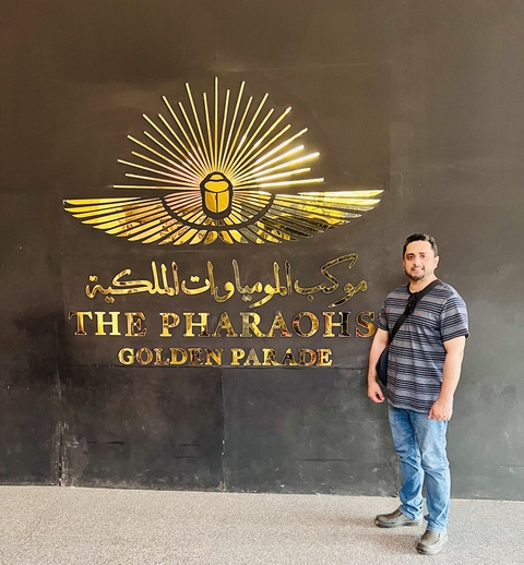 Person standing in front of a golden parade sign.