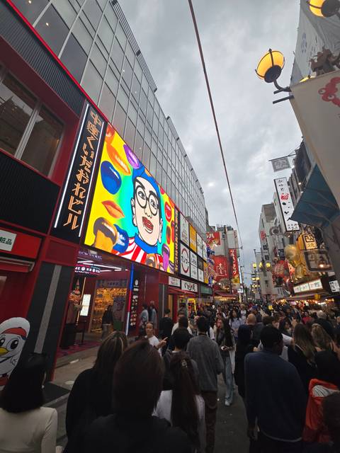 Crowded street with bright billboards and lively atmosphere.