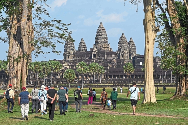 Group of people walking towards the Angkor Wat temple.
