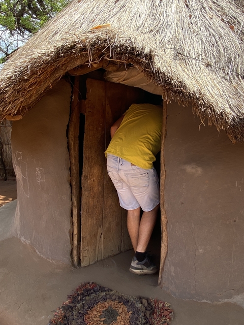 Person entering a traditional mud hut.