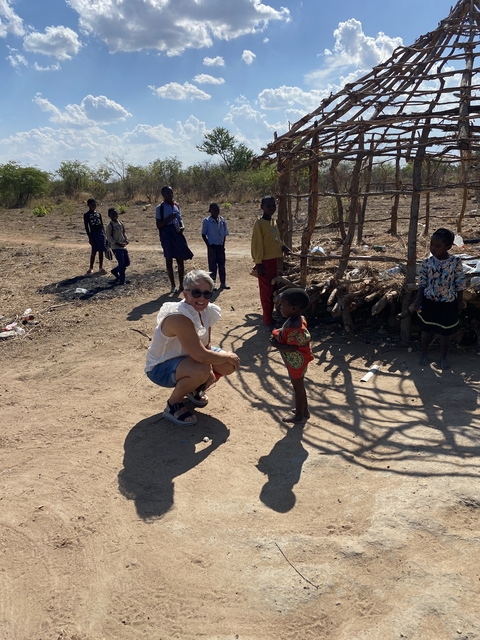 Woman engaging with local children in a rural setting.