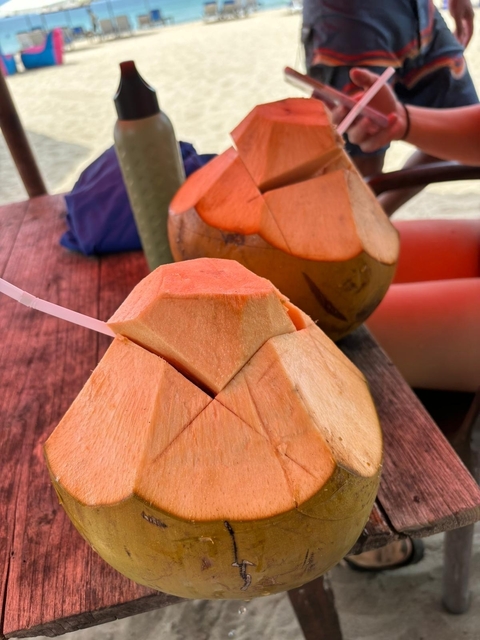       Close-up of coconuts with straws on a wooden table.
  